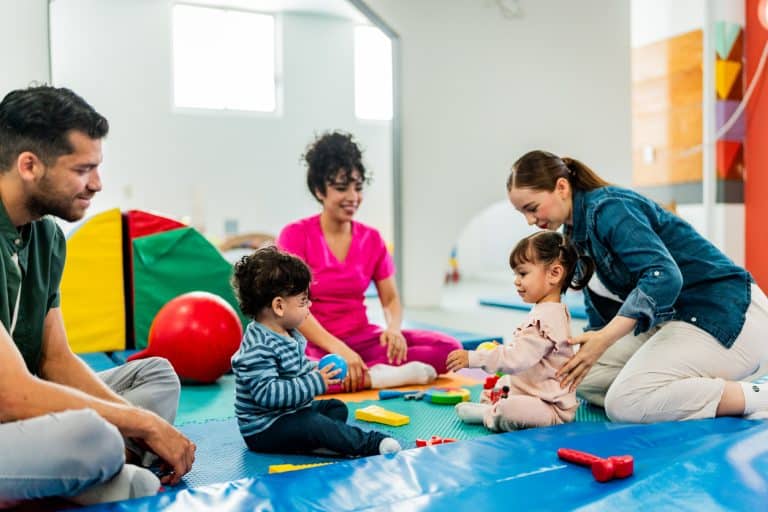 Young parents talking to therapist while kids playing on parents support group.