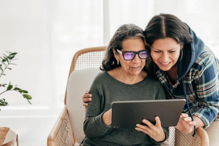 Adult daughter helps her aging mother with a tablet.
